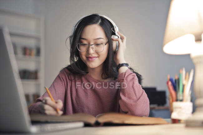 Young woman listens to music while studying — Stock Photo