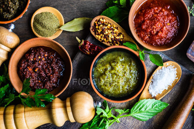 Variety of traditional georgian spices, sauces and herbs served in ceramic bowls on rustic wooden background — Stock Photo