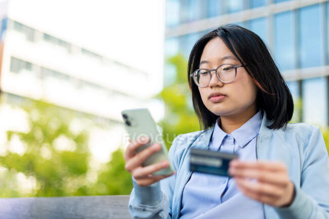 Giovane asiatico adulto utilizzando carta di credito per effettuare l'acquisto su smart phone — Foto stock