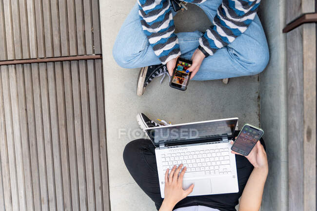 Jeunes assis et utilisant des smartphones avec un ordinateur portable, concept en ligne et espace texte. — Photo de stock
