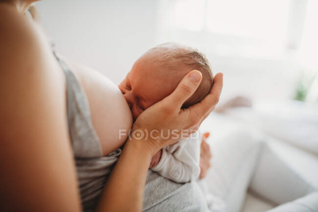 Крупним планом мати тримає голову дитини під час грудного вигодовування — стокове фото