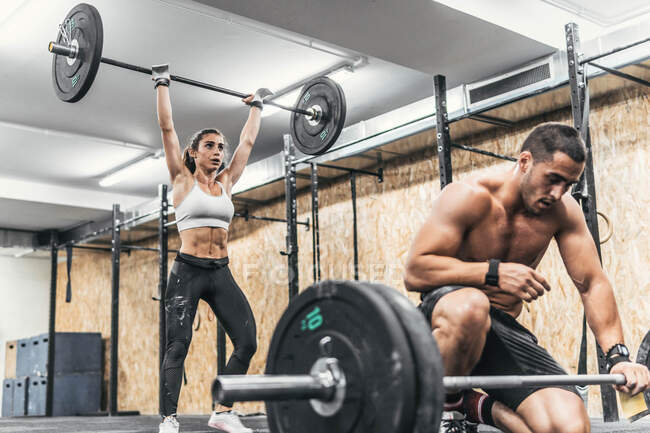 Пара мужчин и женщин, занимающихся тяжелой атлетикой в спортзале, кроссфит — стоковое фото