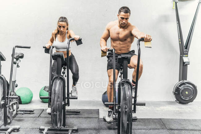 Пара робить велосипед у спортзалі, кросфіт — стокове фото