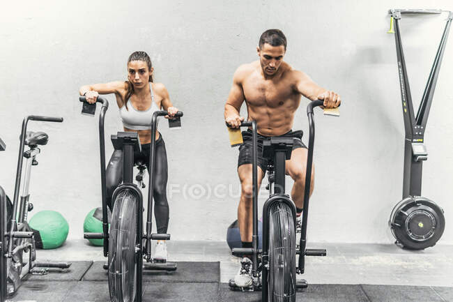 Пара делает велосипед в тренажерном зале, кроссфит — стоковое фото