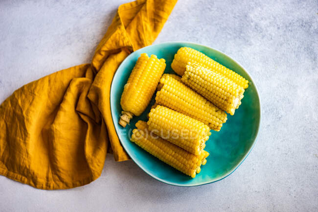 Verduras de maíz hervidas servidas en el plato con sal sobre fondo de hormigón - foto de stock
