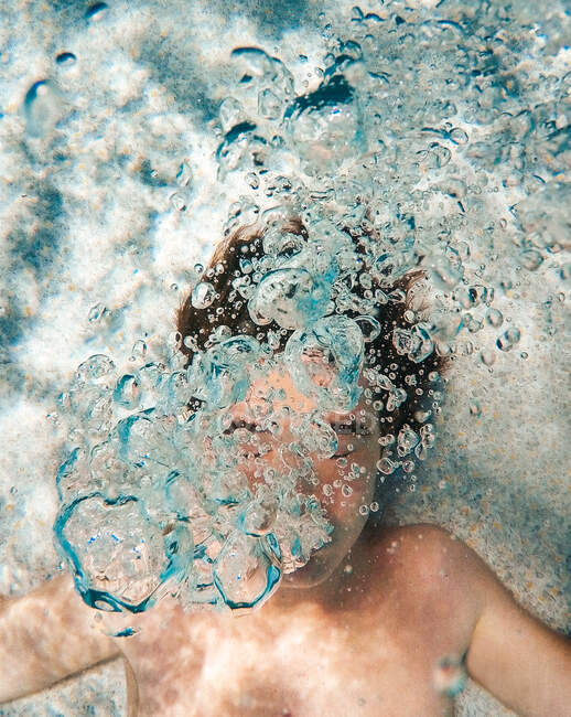 Imagen submarina del adolescente soplando burbujas en una piscina. - foto de stock