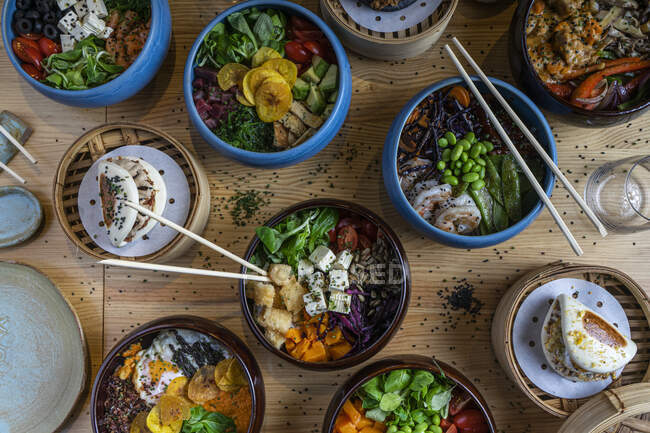 Top view of a few bowls of poke in colorful bowls on a wooden background — Stock Photo