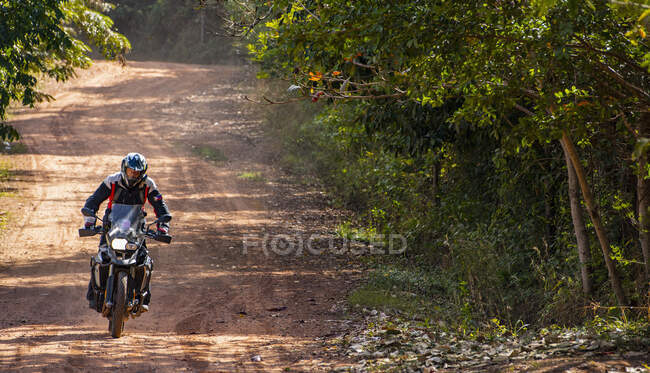 Чоловік їде на своєму пригодницькому мотоциклі по курній дорозі в Камбоджі. — стокове фото