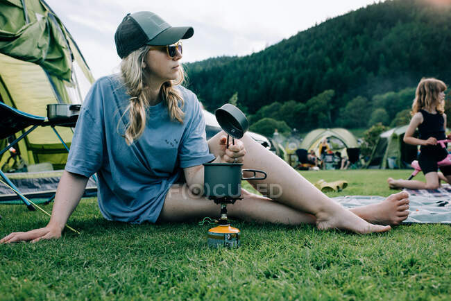 Femme assis avec un poêle portable pendant le camping à Snowdonia — Photo de stock