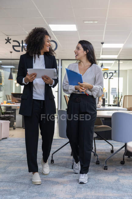 Multicultural coworkers walking in the office and having a conversation. — Stock Photo