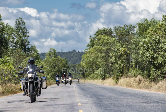 Hombres montando sus motos de aventura en la carretera del campo en Camboya - foto de stock