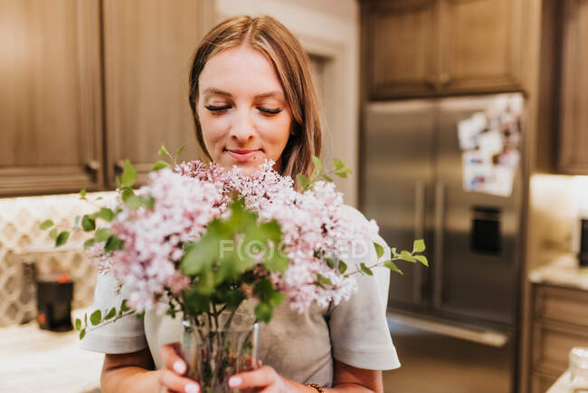 Mulher bonita com buquê de flores em casa — Fotografia de Stock