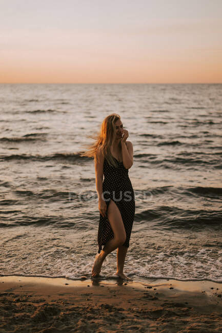 Молода жінка стоїть, усміхаючись біля моря.. — стокове фото