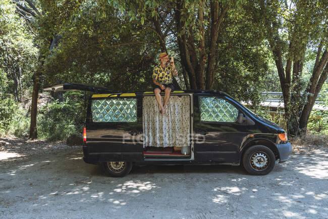 Voyageur homme assis sur le toit du camping-car — Photo de stock