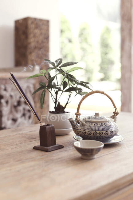 Чайный сервиз и ароматические палочки на деревянном столе. — стоковое фото