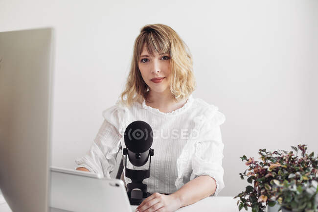 Mulher bonita em um espaço de trabalho com um tablet, microfone, computador — Fotografia de Stock