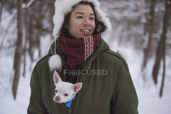 Androgynous asian woman with cute chihuahua inside her jacket in snow — Stock Photo