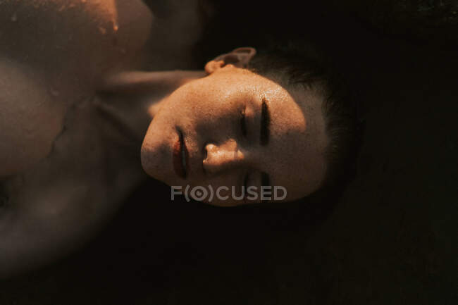 Молода жінка лежить у воді з закритими очима — стокове фото