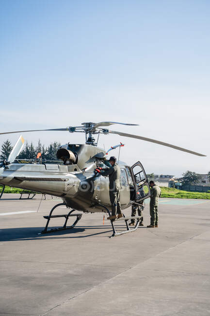 Trois militaires nettoient un hélicoptère au soleil — Photo de stock