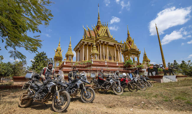 Group of friends posing with motorcycle at temple in Cambodia — Stock Photo