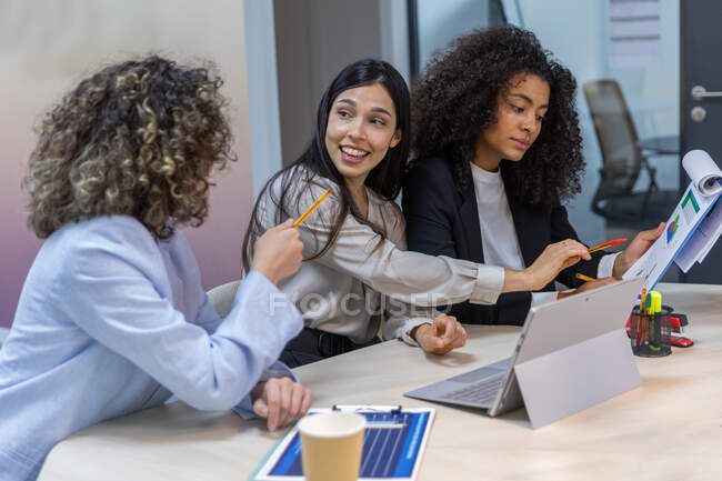 Mulheres de negócios felizes tendo uma reunião no escritório e olhando para gráficos. — Fotografia de Stock