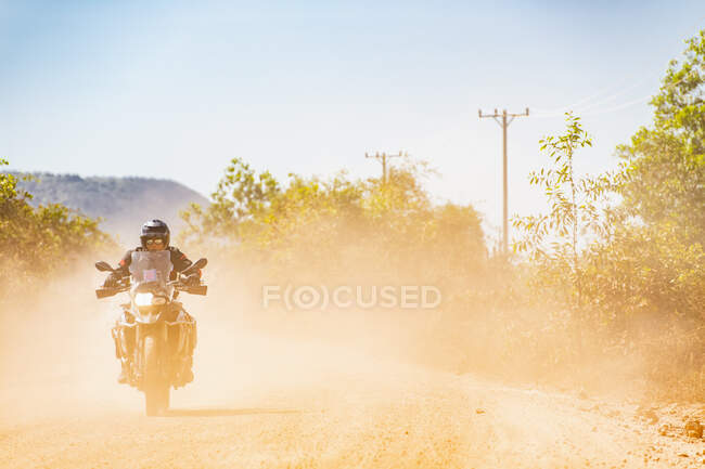 Man riding his adventure motorbike on dusty road in Cambodia — Stock Photo
