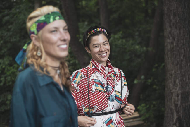 Las mujeres de raza mixta bohemia moda en el bosque juntos sonriendo - foto de stock
