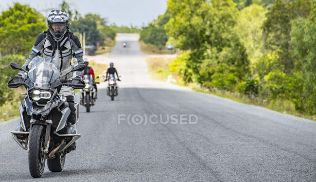 Men riding their adventure motorbikes on straight road in Cambodia — Stock Photo