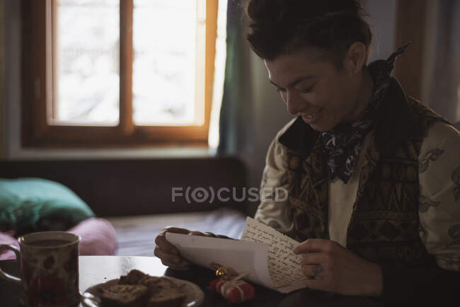 Queer asiático dentro cabina abre regalos y lee carta sonriendo - foto de stock
