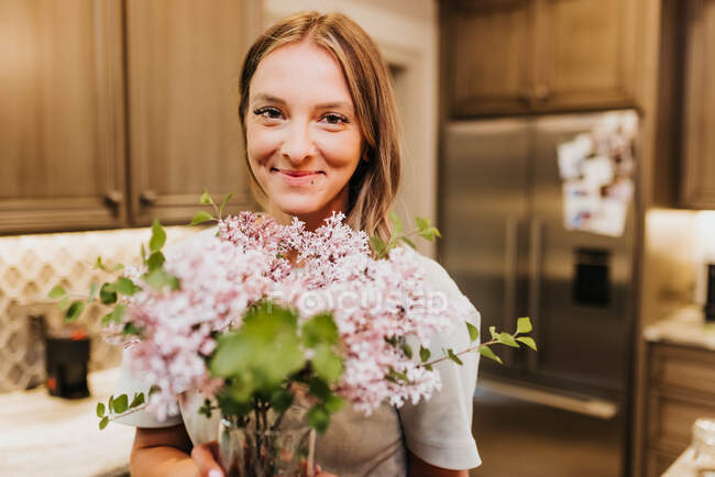 Mulher bonita com flores em casa — Fotografia de Stock
