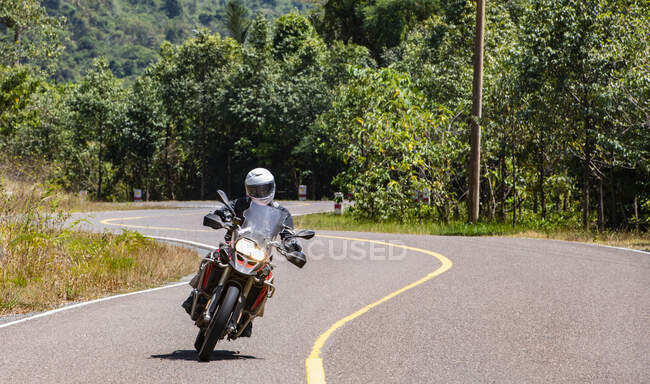 Homem montando sua moto de aventura na estrada ventosa no Camboja — Fotografia de Stock