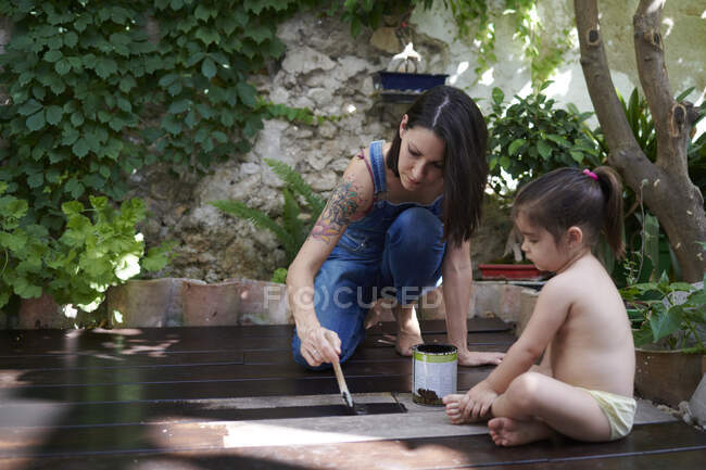 Una mujer pintando la madera en el suelo - foto de stock