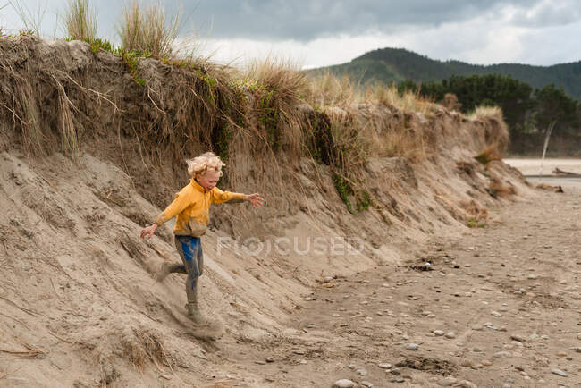 Rubia peludo niño corriendo por la duna de arena en Nueva Zelanda - foto de stock
