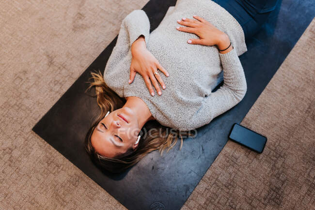 Pregnant woman lying on sofa and reading book — Stock Photo
