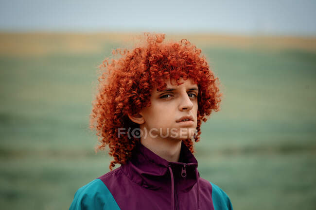 Young guy with red curly hair in 80s sports suit on the field — Stock Photo