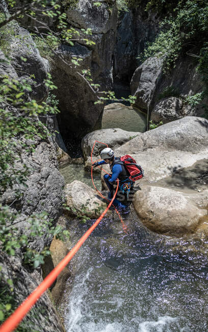 Vue d'angle d'une fille descendant un canyon et tirant la corde vers le bas — Photo de stock