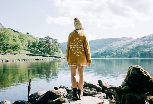 Mujer de pie disfrutando de una vista al lago y la montaña en Gales, Reino Unido - foto de stock