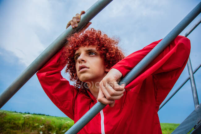 Jovem com cabelo encaracolado vermelho nos anos 80 terno esportivo ao lado de corrimãos de metal nas escadas — Fotografia de Stock