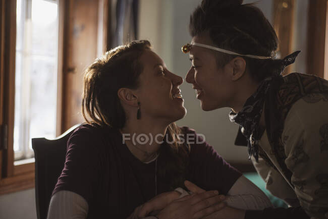 Queer women couple smile and embrace in cottage window in czechia — Stock Photo
