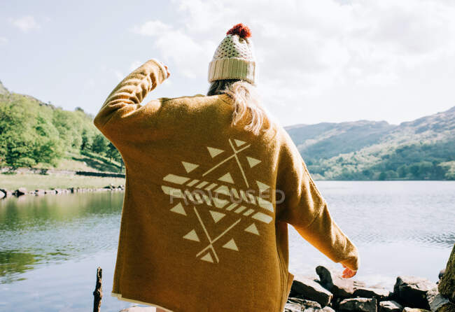 Woman wearing aztec cardigan walking by the lake and mountains — Stock Photo
