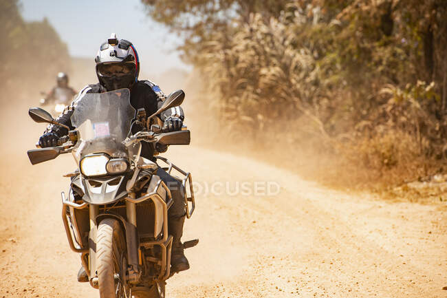 Mann fährt mit seinem Abenteuer-Motorrad auf staubiger Straße in Kambodscha — Stockfoto
