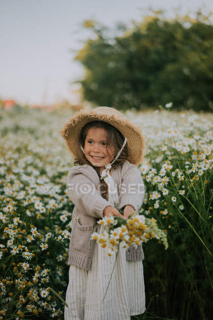 Ein kleines Mädchen hält einen Strauß vor dem Hintergrund des Feldes. — Stockfoto