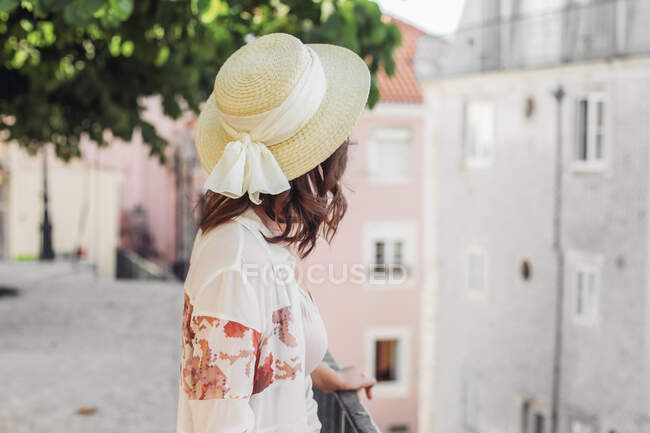 Woman in straw hat with a bow from the back in an European city — Stock Photo