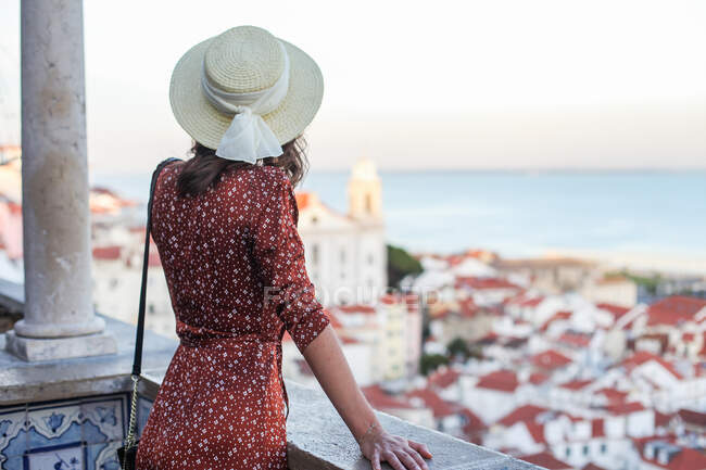 Женщина в соломенной шляпе и коричневом платье на крыше в Лиссабоне — стоковое фото