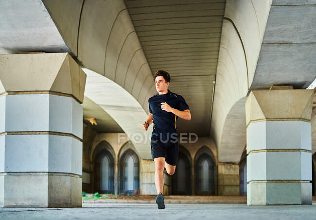 Deportista corriendo bajo un puente - foto de stock