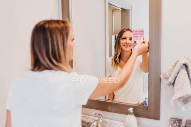 Mujer joven aplicando crema cosmética en el baño - foto de stock