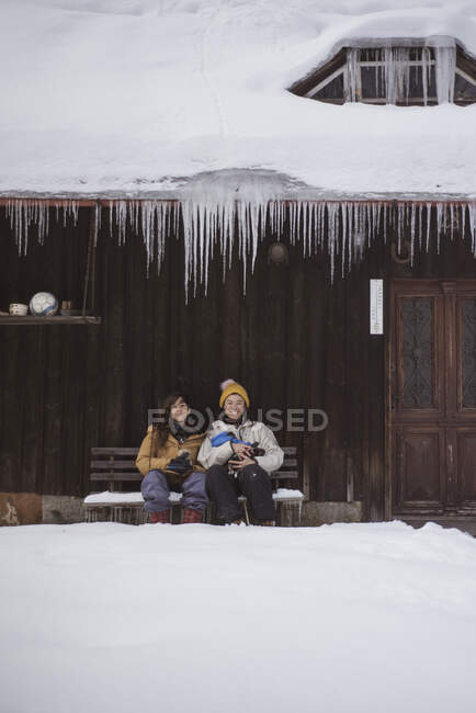 Queer women couple smile and hold dogs outside frozen winter cabin — Stock Photo