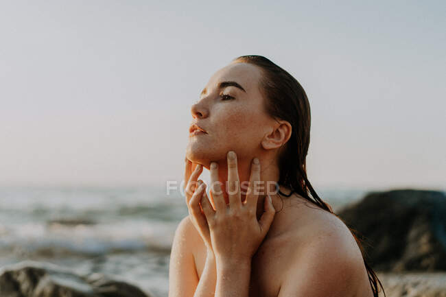Jovem mulher sentada junto ao mar — Fotografia de Stock