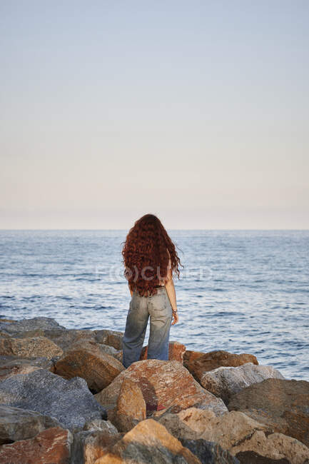 Jeune rousse femme sur son dos regarde vers la mer — Photo de stock