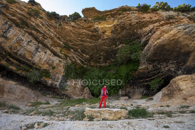 Una mujer haciendo senderismo bajo un sendero escénico bajo un saliente gigante Cuevas de Zaén, pueblo de Zaén, Campo de San Juan, Moratalla, Regin de Murcia, Espaa - foto de stock